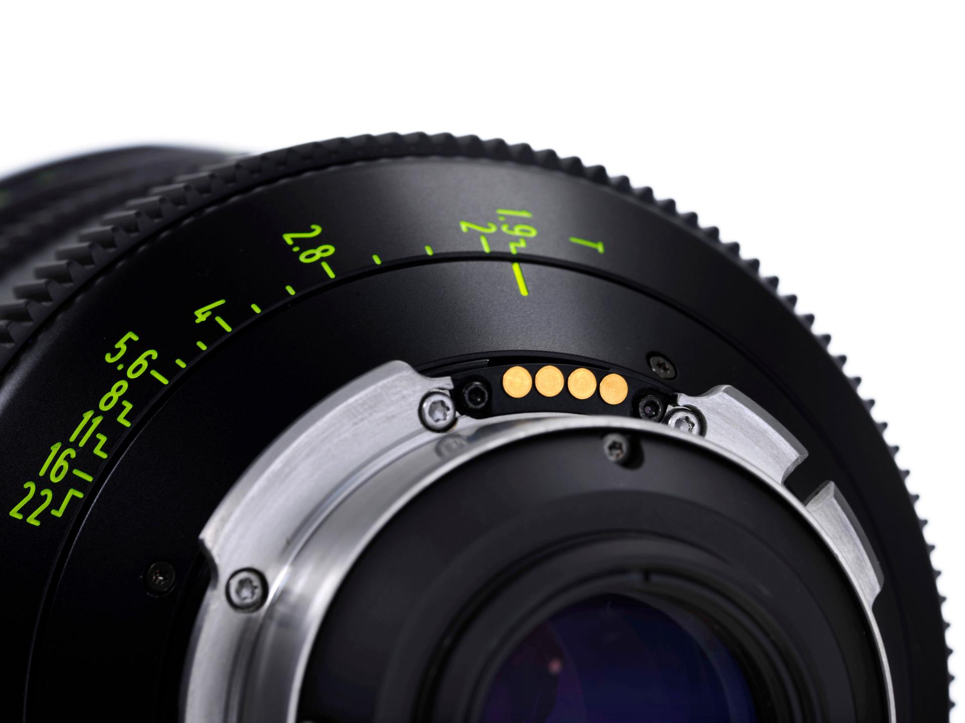 Close-up view of a ZEISS camera lens showing detailed aperture markings and electronic contact points.