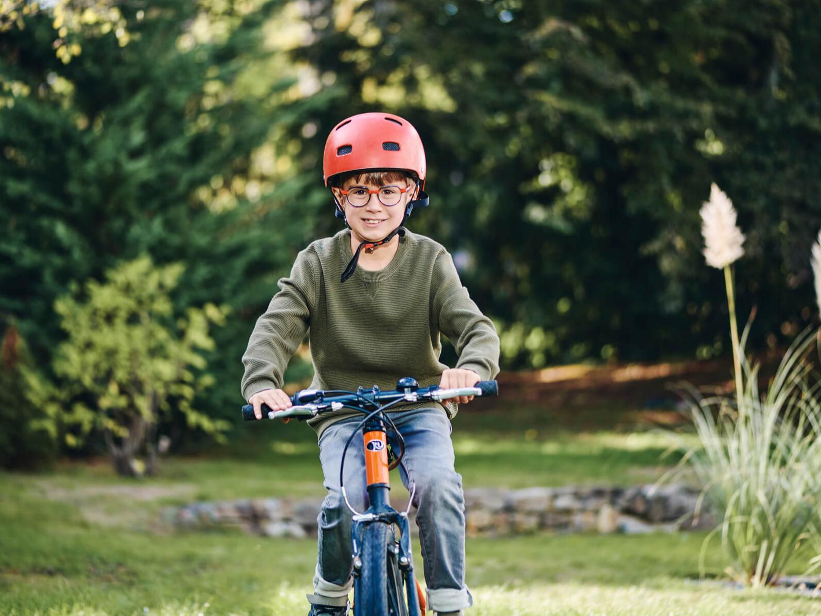 戴着蔡司近视眼管理镜片的小男孩在外面骑自行车。