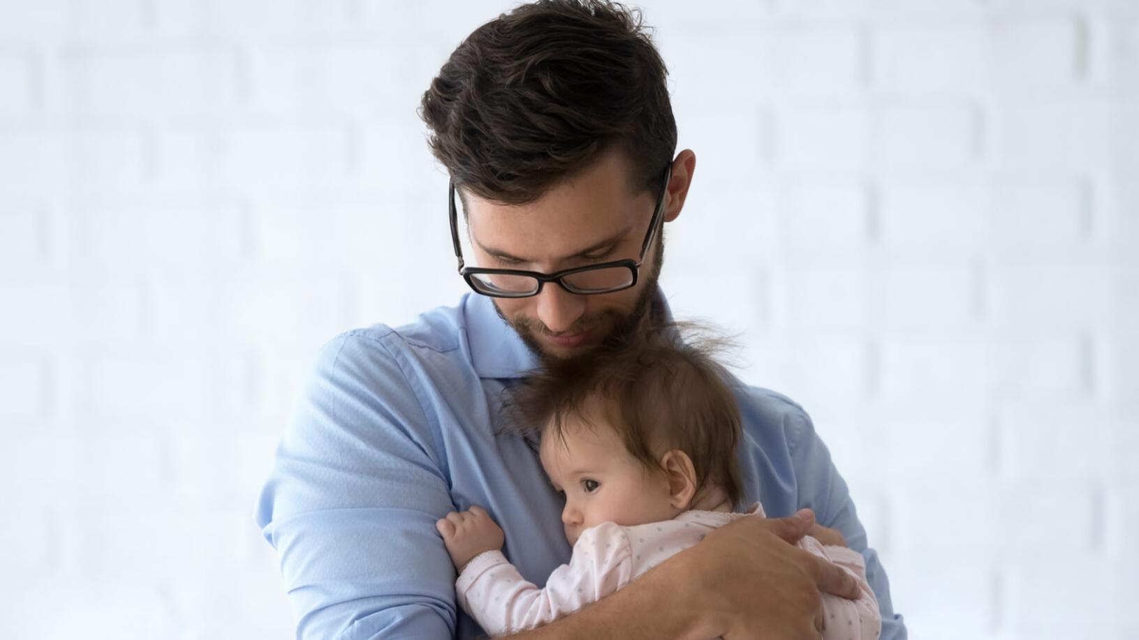 一名戴眼镜的近视男子抱着一个幼儿。