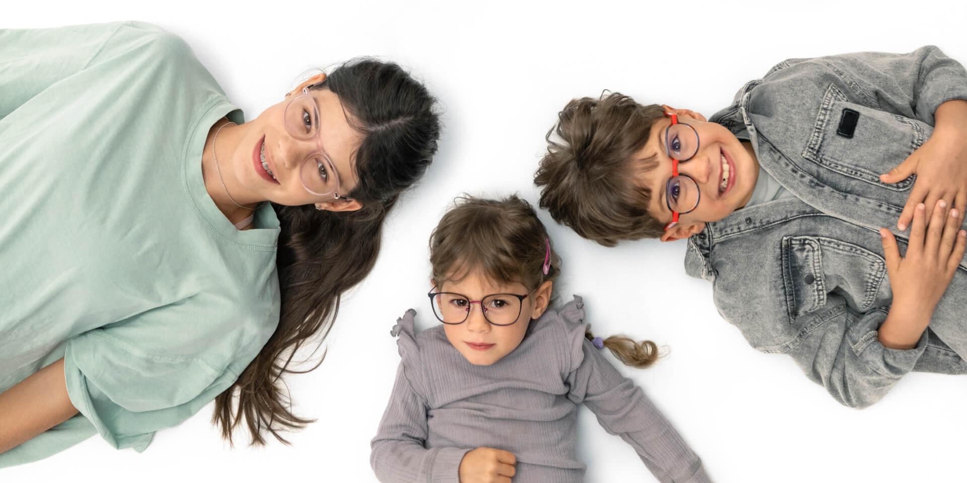 一名青少年和两名年幼的孩子躺在地板上，戴着蔡司近视镜片。