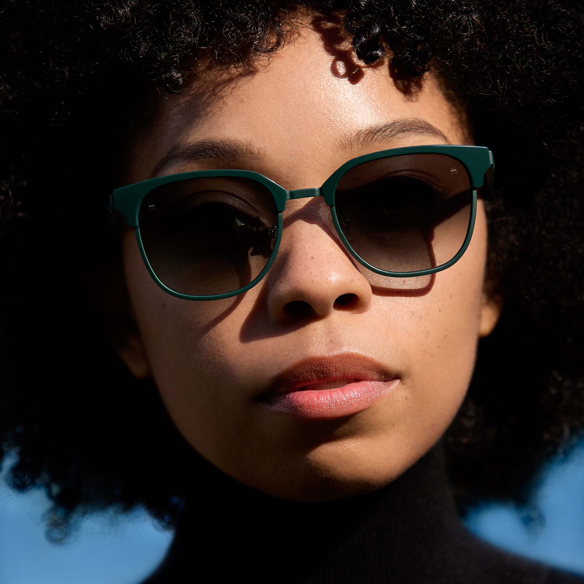 一位女士佩戴绿色镜框，镜片呈渐变色。 